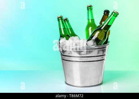 Flaschen Bier in Eis Löffel auf farbigen Hintergrund Stockfoto