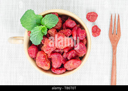 Getrocknete Erdbeeren in weißer Schale auf Tischdecke Hintergrund. Stockfoto