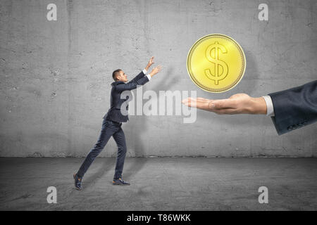 Seite in voller Länge ansehen der kleinen Unternehmer erreichen, die für große Gold Münze schweben über riesige Hand, die sich aus Rechts. Stockfoto