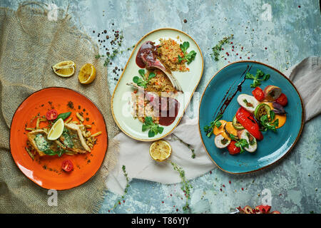 Drei Gerichte mit Lamm Rippen gegrillter Fisch mit gegrilltem Gemüse svrhu Aussicht auf grauem Hintergrund Stockfoto