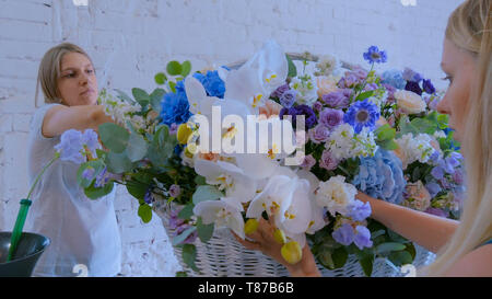 Zwei Frauen, Floristen, großen floralen Korb mit Blumen Flower Shop Stockfoto