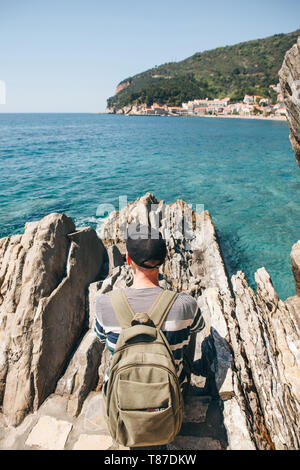 Touristen mit einem Rucksack in der Nähe des Meeres. Allein reisen. In die Ferne schaut. Stockfoto