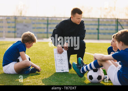 Fußball-Trainer coaching Kinder. Fußball-Fußball-Training für Kinder. Junge Trainer unterrichten die Kinder am Fußballplatz. Fußball Taktik erziehen Stockfoto