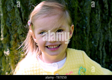 Portrait von kleinen Mädchen stehen und Stamm des alten Baumes Stockfoto