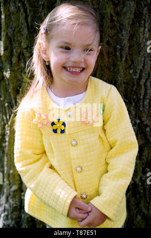 Portrait von kleinen Mädchen stehen und Stamm des alten Baumes Stockfoto