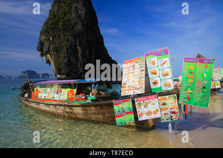 AO NANG (KRABI), Thailand - Januar 3. 2017: Blick auf isolierte Felsen in der Andaman See mit Long Tail Boot im flachen Wasser mit Getränken und Thai Essen Stockfoto