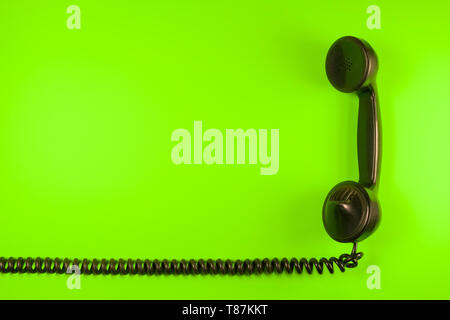 Alte Telefonhörer des frühen zwanzigsten Jahrhunderts mit seinen elastischen Spiralkabel auf neutrale Farbe Hintergrund isoliert Stockfoto