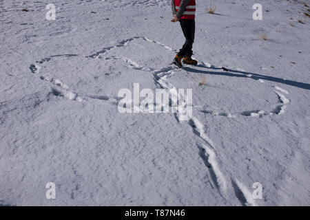 Ein Mann zu Fuß im Schnee und eine Blume mit seinem Schritt. Stockfoto