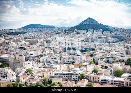 Panoramablick auf die Stadt Athen von der Akropolis mit dem Lycabettus Griechenland / ATHEN, Griechenland - Ein Panoramablick von der Akropolis schweift über die moderne Metropole Athen in Richtung Lycabettus, dem höchsten Punkt der Stadt mit 277 Metern (908 Fuß) über dem Meeresspiegel. Die antike Zitadelle, die zum UNESCO-Weltkulturerbe gehört, überblickt Athen seit über 2.500 Jahren und bietet einen Aussichtspunkt, der den Kontrast zwischen den antiken Fundamenten der Stadt und ihrer zeitgenössischen Stadtentwicklung in ein scharfes Relief wirft. Stockfoto