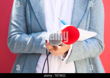 Reporterin bei Pressekonferenz, Schreiben von Notizen, mit Mikrofon Stockfoto
