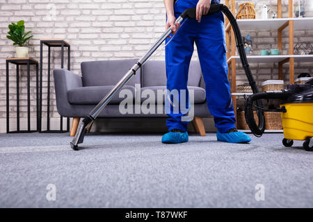 Menschliche Reinigung Teppich Im Wohnzimmer mit Staubsauger zu Hause Stockfoto