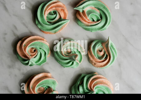 Hausgemachte rainbow meringue Küsse, soft Peach und Minze Farben, Tropfen romantischen rosa auf Marmor Hintergrund von oben. Stockfoto