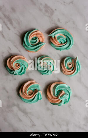 Hausgemachte rainbow meringue Küsse, soft Peach und Minze Farben, Tropfen romantischen rosa auf Marmor Hintergrund von oben. Stockfoto