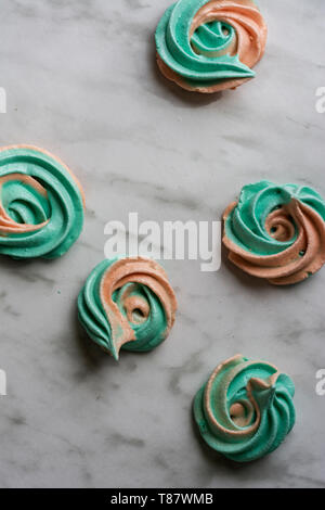 Hausgemachte rainbow meringue Küsse, soft Peach und Minze Farben, Tropfen romantischen rosa auf Marmor Hintergrund von oben. Stockfoto