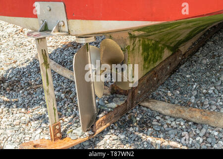 Zurück von einem traditionellen Fischerboot mit dem Propeller und Ruder, am Strand in dem kleinen Fischerdorf Cadgwith, Cornwall, England, Großbritannien Stockfoto