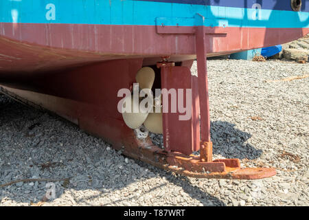 Zurück von einem traditionellen Fischerboot mit dem Propeller und Ruder, am Strand in dem kleinen Fischerdorf Cadgwith, Cornwall, England, Großbritannien Stockfoto