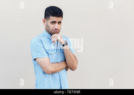 Portrait von traurig allein gut aussehender Junge Bartgeier Geschäftsmann in blaues Hemd stehen und an der Kamera mit Traurigkeit oder Angst Gesicht. indoor Studio shot Stockfoto
