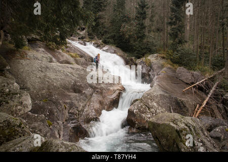 Frau, die in der Nähe von starken Fluss im Wald Stockfoto