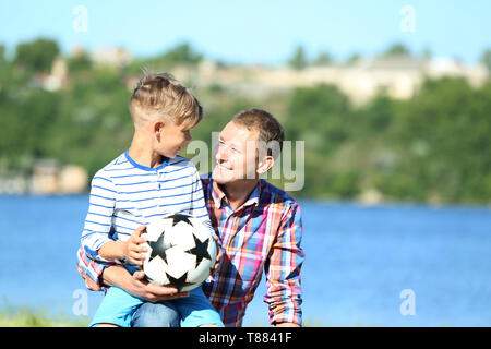 Gerne Vater und Sohn mit Fußball in der Nähe von Fluss Stockfoto