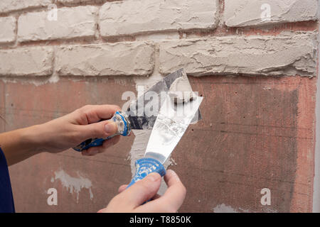 Gipser arbeitet mit zwei Spatel auftragen Putz an der Wand Stockfoto