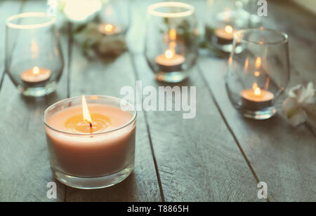 Schöne brennende Kerzen in Gläsern auf hölzernen Tisch Stockfoto