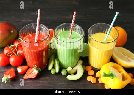 Gläser mit frischen leckeren Smoothies und Zutaten auf Tisch Stockfoto