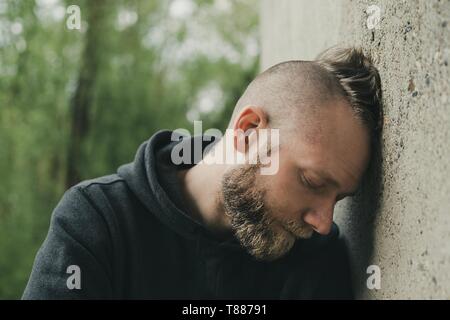 Deprimiert und einsamen Mann seinen Kopf gegen eine Wand. Stockfoto