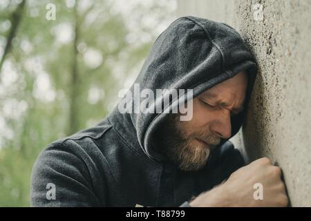 Mann traurig seinen Kopf gegen eine Wand gelehnt Stockfoto