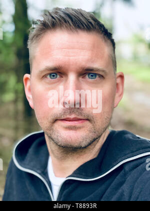 Schöne blaue Augen Mitte nach kaukasischen Close up up Gesicht portrait Natur mit Wald Hintergrund Stockfoto