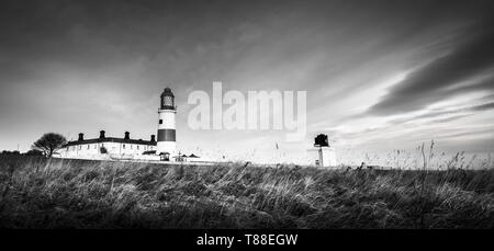 Eine kalte aber glühende winter Sonnenaufgang mit Frost auf dem hohen Gras an der nordöstlichen Küste von National Trust Souter Leuchtturm Stockfoto