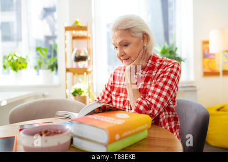 Angenehme schöne ältere Frau ihre Wange Holding Stockfoto