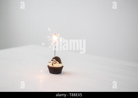 Essen und Urlaub Konzept - Geburtstag Cupcake mit Wunderkerzen auf weißem Hintergrund mit Kopie Raum Stockfoto