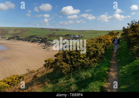 Weibliche zu Fuß in Richtung Putsborough Strand von der Küste Weg hoch auf Baggy Punkt Landspitze Devon Stockfoto