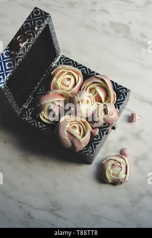 Rosa Baisers, wie Rosen geprägt. In einer Blue Box, Romantische appetitlich Baisers zum Valentinstag. Stockfoto