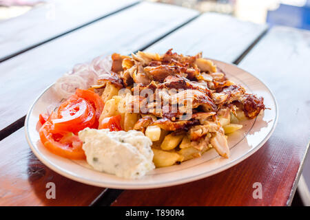 Leckere griechische Gyros mit Pommes frites, Gemüse und Tzatziki Soße auf weiße Platte Stockfoto