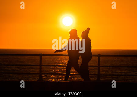 Aberystwyth Wales UK, Samstag, 11. Mai 2019 Deutschland Wetter: Menschen sind gegen den herrlichen Sonnenuntergang Silhouette, wie Sie XXXXXX in Aberystwyth auf der Cardigan Bay Küste, West Wales. Das Wetter soll in der kommenden Woche wieder wärmer als Zeit der unruhigen kalten Bedingungen zu erhalten. Photo credit Keith Morris/Alamy leben Nachrichten Stockfoto