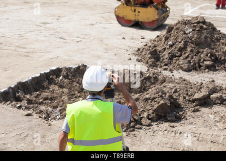 Vermessungsingenieur arbeiten mit theodoliten an der Baustelle Stockfoto