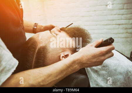 Seitenansicht des Ernteguts männliche Gesicht im Friseursalon schneiden roten Bart und Friseur hand Haarschneider Stockfoto