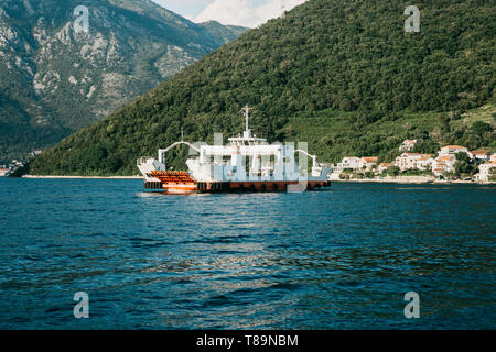 Eine Fähre Fahrzeuge und Personen zu transportieren kreuzt die Bucht in Montenegro und nähert sich der Stadt. Stockfoto