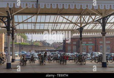 Der Bahnhof York Plattform unter einer aufwändigen Baldachin aus dem 19. Jahrhundert mit Fahrrädern unter. Die historische Stadtmauer sind in der Ferne. Stockfoto