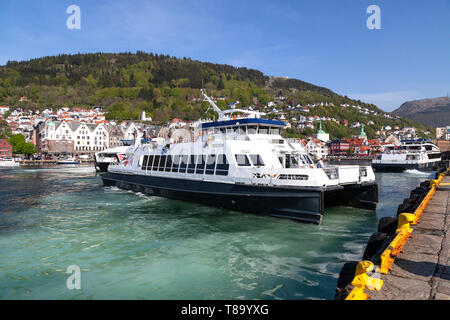 Lokale Fahrgast Katamaran Teisten aus Strandkaien Anschlußklemme n Hafen von Bergen, Norwegen abfliegen. Hanseatic Bryggen im Hintergrund. Stockfoto