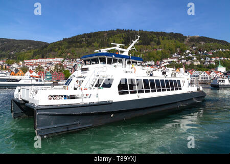 Lokale Fahrgast Katamaran Teisten aus Strandkaien Anschlußklemme n Hafen von Bergen, Norwegen abfliegen. Hanseatic Bryggen im Hintergrund. Stockfoto