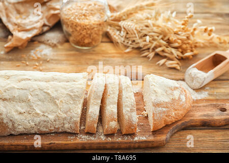 In Scheiben geschnitten Brot aus Weizen mit Mehl auf Holzbrett Stockfoto
