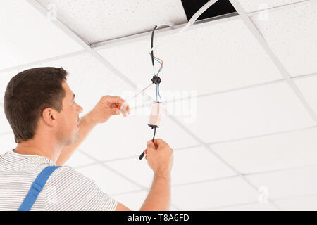 Elektriker die Messung der Spannung der Kabel an der Decke im Innenbereich Stockfoto