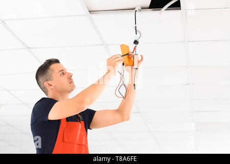 Elektriker die Messung der Spannung der Kabel an der Decke im Innenbereich Stockfoto