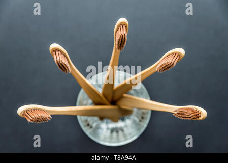 Bambus Zahnbürsten in Glas auf dunklen rauen Hintergrund. Kunststoff-Konzept Stockfoto