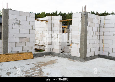 Die Wände von einem Haus der weißen Stein mit Stahlbeton Säulen, an dessen Ende es gibt gerippten Stangen, Holzschalung sichtbar von der Stockfoto