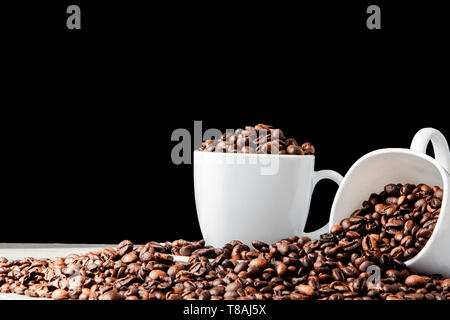 In weiße Tasse schwarzen Kaffee und Kaffeebohnen auf schwarzem Hintergrund. Ansicht von oben, Platz für Text Stockfoto