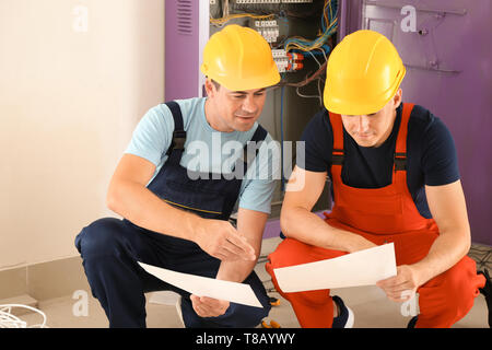 Zwei Elektriker mit Haus Plan in der Nähe der Verteilung im Innenbereich Stockfoto