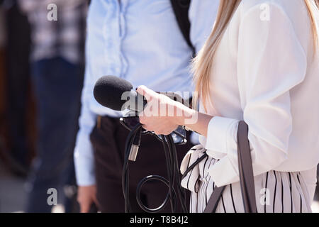 Weibliche Reporter mit Mikrofon an einem freien Medien event Stockfoto